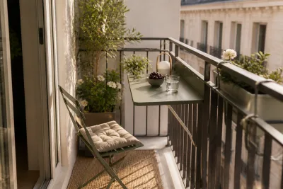 Petit balcon aménagé : tablette de rambarde rabattable, deux chaises pliantes rangées au mur et jardinières étroites, passage dégagé